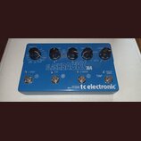 Modrý efekt pedál s nápisem FLASHBACK X4 a logem tc electronic. Na horní části jsou čtyři ovládací knoflíky s popisky TONEPRINT, TIME, FEEDBACK a DEL…