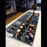 Fotografie znázorňuje elektronickou desku s osazenými součástkami, která je připevněna k hliníkovému chladiči. Na desce jsou vidět řady zlatavých ele…
