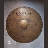 Kruhová mosazná činely s kladeným povrchem. V horní části je černý nápis „istanbul“ a pod ním menší text „Mehmet Handmade cymbals from Turkey“. Ve sp…