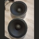 Dvě černé reproduktorové membrány s bílým vnějším rámem. Povrchy jsou hladké a bez viditelných poškození. Na fotografiích nejsou žádné čitelné značky…