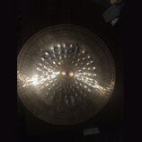 Kruhový mosazný činel s koncentrickými drážkami na povrchu. Na horní části je viditelný tmavý nápis PAISTE. Povrch vykazuje odrazy světla a drobné ne…