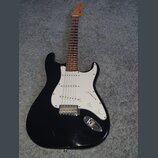 Černá elektrická kytara s bílým pickguardem a hnedým hmatníkem. Na hlavě krku je viditelné logo Fender. Nástroj má tři snímače typu single-coil, tři…