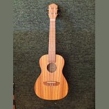Dřevěný nástroj typu ukulele s přirozenou barvou a výraznou sletovanou strukturou dřeva. Na hlavě je viditelné logo ve tvaru stylizovaného písmena „C…