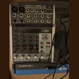 Stříbrný mixážní pult značky behringer s označením XENYX Q802USB. Zařízení obsahuje čtyři vstupní kanály s ovládacími prvky pro GAIN, EQ a LEVEL, USB…