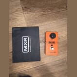 Oranžový kytarový efekt s černým ovládacím knoflíkem a nápisy SPEED, OUTPUT, INPUT a MXR. Ve spodní části je vyražen text phase 90. Vedle efektu leží…