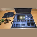 Modrý digitální mixovací pult Magic O M050 v hliníkovém přepravním kufru. Zařízení má centrální displej, několik otočných knoflíků a velké množství č…