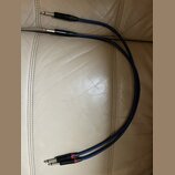 Dvě modré audio kabeláže s konektory typu jack. Na jednom konci jsou oba konektory stříbrné, na druhém konci mají černé kryty s červenými prstenci. N…