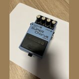 Modrý kytarový efekt s černým spínacím pedálem. Na horní straně jsou tři bílé ovládací knoflíky a nápisy SUPER Chorus, CH-1, OUTPUT A (MONO) a INPUT.…