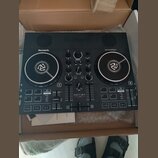 Černý DJ kontrolér značky Numark s nápisem PARTY DJ CONTROLLER. Uprostřed je uveden model PARTY MIX LIVE. Zařízení obsahuje dva jog-wheels, několik p…