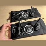 Dvě černé zipové pouzdra s bílým logem AKG. V každém pouzdře je černý mikrofon s připojeným kabelem a držákem. Na spodním mikrofonu je nápis PHANTOM…