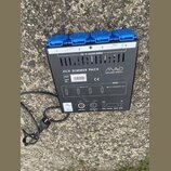 Černý čtyřkanálový dimer s modrými zásuvkami. Na zařízení je nápis 4CH DIMMER PACK a logo MAD INTELLIGENT QUALITY. Jsou zde uvedeny údaje Model: MAD…