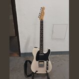 Bílá elektrická kytara s černým pickguardem a hnědým hmatníkem. Na hlavě je viditelné logo Fender. Nástroj má jeden humbucker v pozici mostu a jeden…