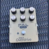 Zlatý kytarový pedál s nápisem PAL 800 a GOLD Overdrive. Na horní straně se nachází šest otočných knoflíků s popisky VOLUME, PRESENCE, GAIN, BASS, MI…