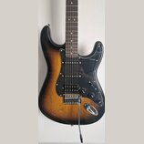 Elektrická kytara s trupem v barevnosti sunburst a černým pickguardem. Nástroj má tři snímače typu single-coil, jeden ovladač VOLUME a dva ovladače T…