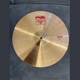 Zlatavý kovový činel s viditelným broušením. Na povrchu je červené logo Paiste 2002 s nápisy TRADE MARK a MADE IN SWITZERLAND. Na pravé straně je čer…