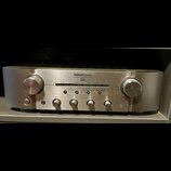 Stříbrný integrovaný zesilovač s kovovým povrchem. Na předním panelu je nápis marantz a pod ním INTEGRATED AMPLIFIER PM8005. Zařízení má dva velké ov…