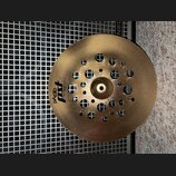 Zlatavý kovový činel s několika průřezem v podobě otvorů různých velikostí. Na povrchu je černý nápis pAiste PST X a pod ním menší text 14" BRASS FLA…
