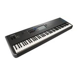 Černý digitální klavír s bílými a černými klávesami. Na levé straně je viditelné logo YAMAHA a v pravém horním rohu nápis MODX. Nástroj disponuje dis…