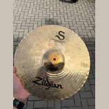 Zlatý mosazný činel s viditelným rýhováním povrchu. Na horní části je černé logo ve tvaru písmene „S“ a nápis „MASTERSOUND HIHAT BOTTOM 14"/36 cm“. V…