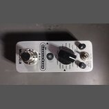 Stříbrný efekt pedál z kovu s nápisy MOOER a Groove Loop. Na horní straně se nachází stoupací spínač, černý oválný volič s popisy stylů (Blues1, Blue…