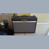 Kytarový kombo zesilovač značky Fender v tmavě šedém provedení s černou madlou. Na přední straně je stříbrný štítek s nápisy FENDER a BASSBREAKER™. P…