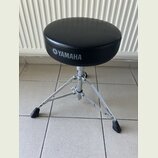 Černý polstrovaný hudební židliček s kovovým chromovaným stativem a gumovými koncovkami nohou. Na boku sedáku je bílý nápis YAMAHA s doprovodným loge…