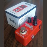 Červený efekt pedál s nápisy tc electronic, HALL OF FAME 2 MINI a BYPASS. Na horní straně jsou tři černé oválové ovládací knoflíky a jeden stříbrný k…