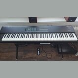 Černý digitální klavír na černém stojanu. Na levé straně je nápis KURZWEIL a vpravo označení SP88 Stage Piano. Horní panel obsahuje ovládací prvky, t…