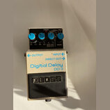 Kytarový efekt pedál značky BOSS, model Digital Delay DD-3. Má stříbrné kovové tělo s modrými ovládacími knoflíky a černým spínacím pedálem. Na horní…