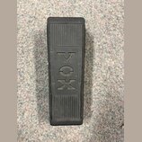Černý sustain pedál s žebrovaným povrchem. Uprostřed je vyražen nápis VOX, který je v rámečku dopojen na text AMPLIFIER zleva a INSTRUMENT zprava. Po…