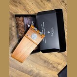 Dřevěný stompbox v černé krabici s výplní z dřevěné štěpky. Na přístroji je vidět nápis „WildDog STOMP“ s ikonou tlapky a označení „RUNTIP“. Vnitřní…