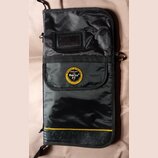 Černý textilní obal na hudební nástroj s žlutým pruhem v dolní části. Uprostřed je kulatý žlutý štít s nápisy ROCKBAG by Warwick, proudly made with R…