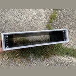 Prodloužený obdélníkový hliníkový rám stříbrné barvy s černým vnitřním dnem. V levé a pravé části jsou vidět černé panely s otvory pro montáž. Na pov…