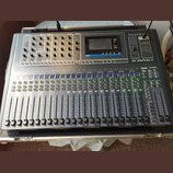 Míchací pult v transportním kufru s nápisy Soundcraft a Si IMPACT. Zařízení obsahuje digitální displej, početné posuvníky, knoflíky a tlačítka v šedé…