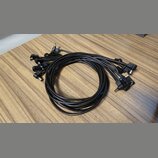 Na fotografii je černý vícežilový kabel s několika koncovými konektory typu jack. Kabel je svinutý do kruhu a položen na dřevěném povrchu. Na viditel…