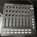 Černý MIDI kontrolér značky novation s nápisem LAUNCH CONTROL XL. Zařízení obsahuje tři řady otočných knoflíků s bílými indikátory, osm posuvníků a d…