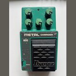 Zelený kytarový efekt s černým pedálem. Na horní části je nápis METAL CHARGER a na pedálu logo Ibanez. V levé části je viditelný nápis MSIC a v dolní…