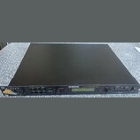 Černý rackový syntetizátor s nápisem ENSONIQ 64 Voice Expandable Synth. Na předním panelu jsou umístěny tlačítka, ovládací prvky a displej, v levém r…