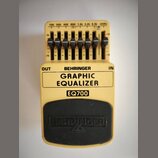 Žlutý kytarový pedál s nápisem BEHRINGER GRAPHIC EQUALIZER a označením modelu EQ700. Horní část obsahuje sedm posuvníků s popisky 100, 200, 400, 800,…