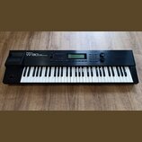 Černý klavírní syntetizátor s bílými a černými klávesami. Na levé straně horního panelu je bílý nápis Roland W-30 MUSIC WORKSTATION. V horní části se…