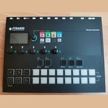 Černý sekvencer s nápisem PYRAMID polyrhythmic 64track sequencer a značkou Squarp instruments. Zařízení obsahuje displej, pět otočných ovladačů, něko…