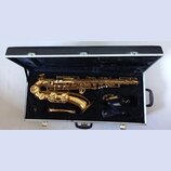 Zlatý saxofon v černém polstrovaném kufru. K nástroji je přiložen munčnípás s nápisem veti a samostatný mouthpiece. Na těle nástroje nejsou žádné čit…