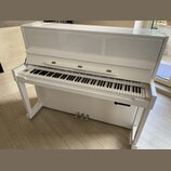 Bílý pianino s glossy povrchem a bílými nohami. Nad klávesnicí je v centru umístěn nápis SAMICK. Nástroj vykazuje čistý povrch bez viditelného opotře…