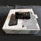 Na bílém kartonovém obalu s nápisy Fender MUSTANG MICRO je položen černý kompaktní kytarový zesilovač Mustang Micro. Zařízení má stříbrný konektor, o…