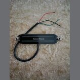 Černý humbucker s kovovými šrouby na okrajích. Uprostřed je bílý nápis Seymour Duncan. Z nástroje vede černý kabel zakončený čtyřmi barevnými vodiči…