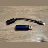 Na fotografii je modrý USB dongle s logem vály a nápisem DRAGONFLY. Vedle něj leží černý adaptér s kabelem, který má na jednom konci USB-C konektor a…
