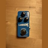 Modrý efekt pedál s nápisy FLASHBACK MINI a tc electronic. Na horní části jsou tři černé ovládací knoflíky s popisky DELAY, F. BACK a LEVEL. V dolní…