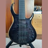Tmavě hnědá basová kytara s výraznou strukturou dřeva a černým hardwarem. Na horním snímači je nápis "Sire Marcus Miller". Nástroj má dva snímače, čt…