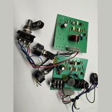 Fotografie zobrazuje dvě zelené elektronické desky s osazenými součástkami a připojené potenciometry a konektor. Na jedné z desek je viditelný nápis…