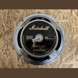 Fotografie znázorňuje zadní stranu reproduktoru s kovovým rámem. Na černém krytu jsou zlaté nápisy Marshall, Vintage BY CELESTION a bílé označení G12…